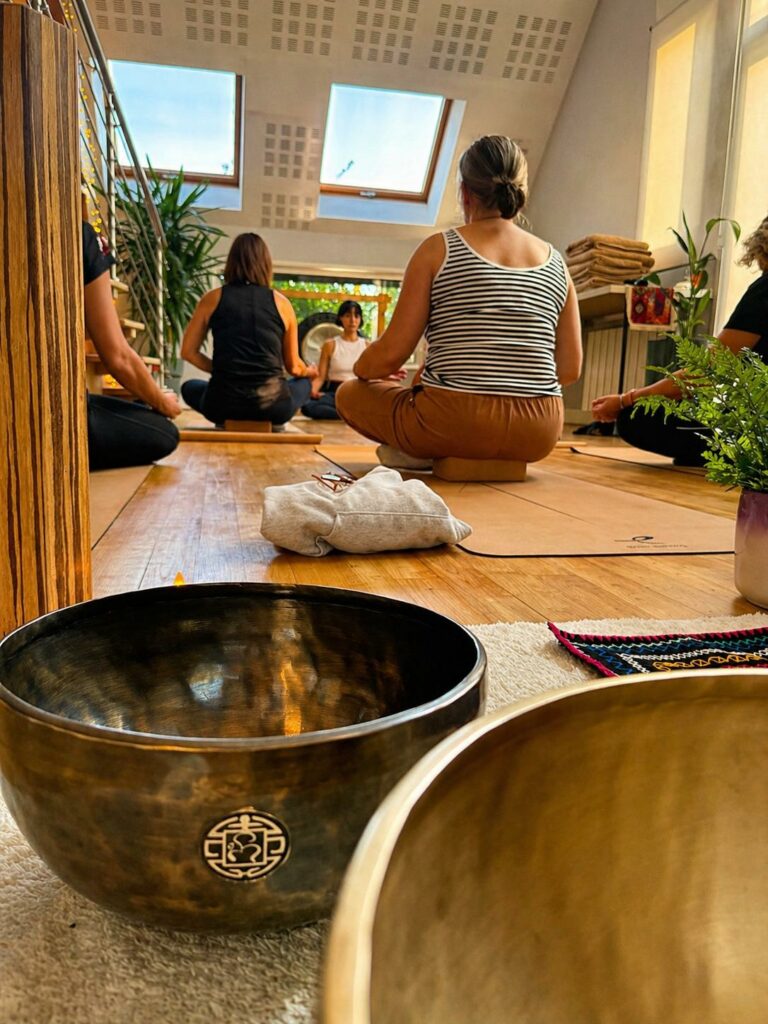 Élèves assis en méditation dans un studio mansardé, avec un bol chantant au premier plan